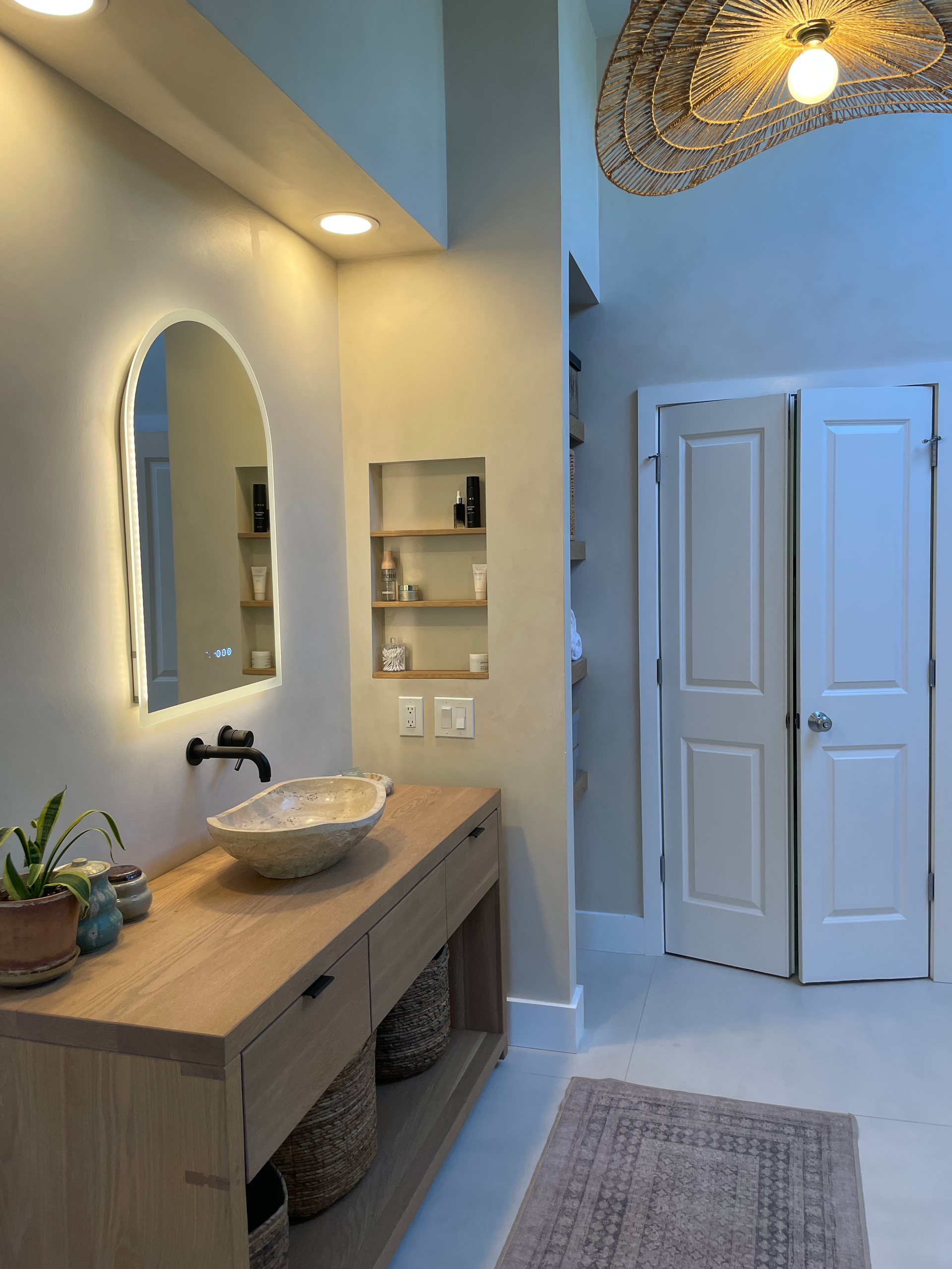 White oak vanity with woven baskets and a stone vessel sink